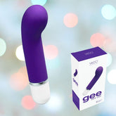 An indigo mini vibrator with a white base, made from medical-grade silicone for safe G-spot stimulation, is displayed next to its packaging. The box features the text "VeDO 'Gee' Mini G-Spot Rechargeable Waterproof Vibrator" and highlights its 10 different modes. The background shimmers with soft, multicolored lights.